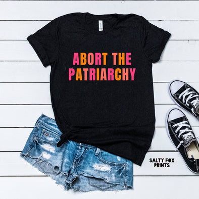 black shirt that says abort the patriarchy in pink and orange font