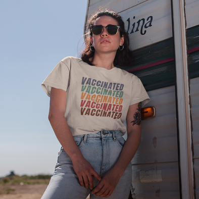 woman leaning on a camper wearing sunglasses and a retro colored vaccinated shirt